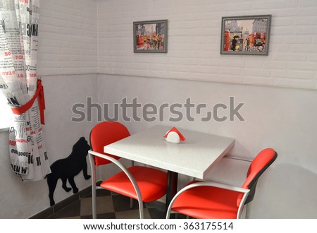 Little table and red chairs in modern cafe. Interior