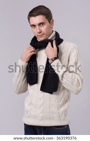 Man in winter knitted clothes standing with arms folded isolated on gray