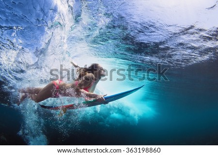 Young girl in bikini - surfer with surf board dive underwater with fun under big ocean wave. Family lifestyle, people water sport lessons and beach swimming activity on summer vacation with child Royalty-Free Stock Photo #363198860