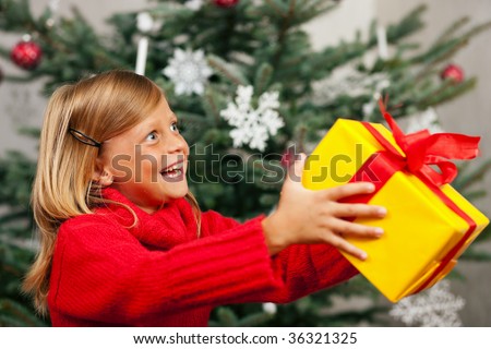 Young girl in front of the Christmas tree showing the world the present she received