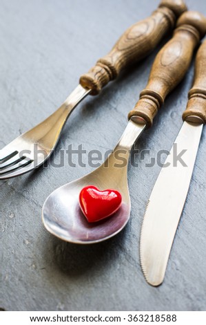 Vintage silverware and heart on rustic wooden background
