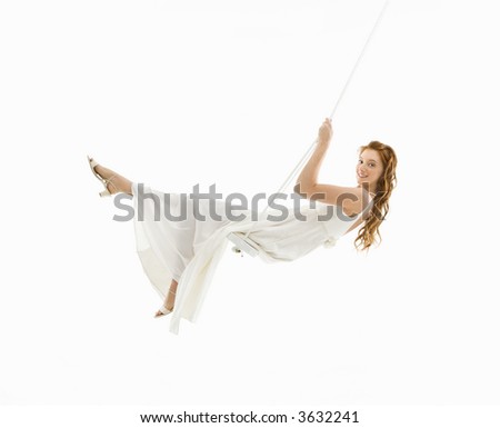 Caucasian bride swinging in swing set and looking at viewer.