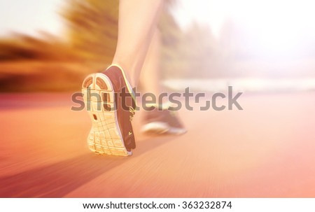 Athlete runner feet running on athletic track, closeup on sport shoe. Strong motion blur and lens flare effect. Colorful tonal photo filter correction.