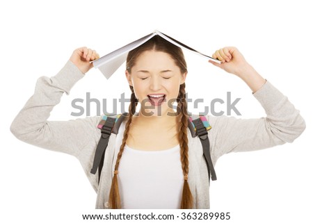 Teen girl with book over her head.