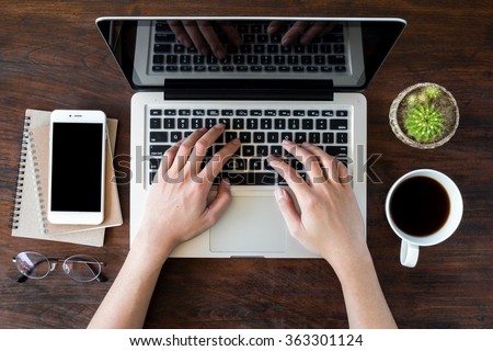 A man is working by using a laptop computer on vintage wooden table. Hands typing on a keyboard. Top view. Royalty-Free Stock Photo #363301124