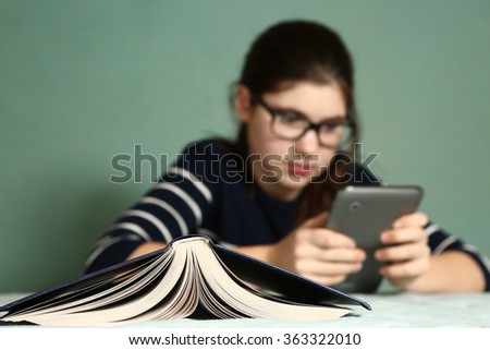 teenager girl in myopia glasses play online game on tablet refuse to read book Royalty-Free Stock Photo #363322010