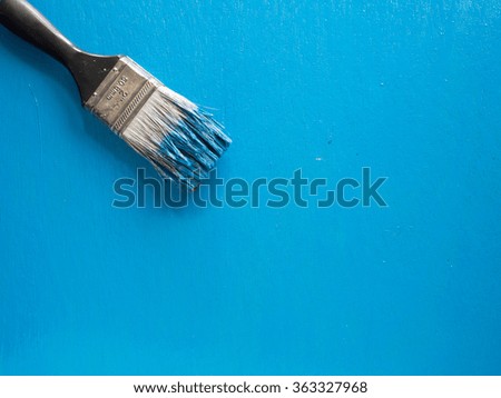 A used paint brush over a blue wooden background,top view