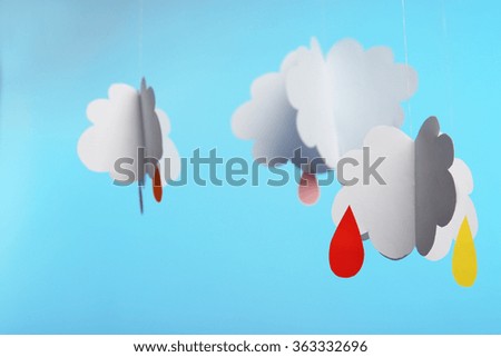 Paper clouds with drops on blue background
