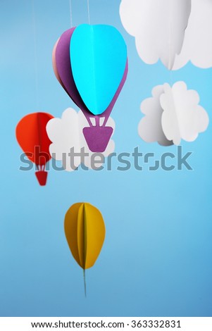 Paper clouds and airship on blue background