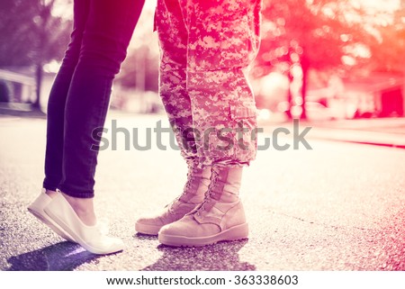 Young military couple kissing each other, homecoming concept, soft focus, cross process  toning applied, light leak in the corner Royalty-Free Stock Photo #363338603