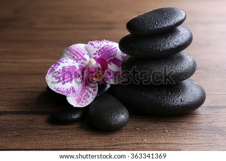 Black pebbles with orchid on wooden background