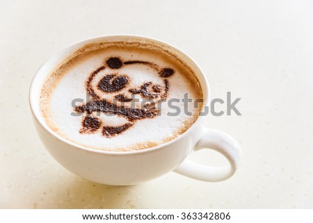 Top view of a giant panda (or panda bear) shape foam art of a cappuccino cup with saucer on wooden table background with copy space for your illustration. Latte art drawing cafe cup of cute panda face