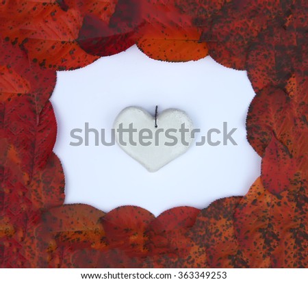 Decorative handmade ceramic heart in frame of red autumn leaves