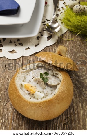 Traditional polish white borscht with eggs and sausage in bread for easter