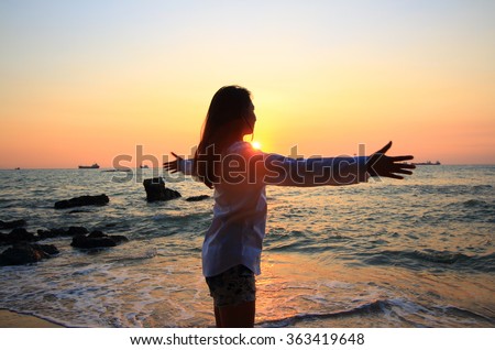 Enjoyment - free happy woman enjoying sunset. Beautiful woman in white dress embracing the golden sunshine glow of sunset with arms outspread and face raised in sky enjoying peace, serenity in nature