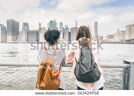 Two women looking at New York skyline - Multiethnic girls leaning on a railing and watching at cityscape Royalty-Free Stock Photo #363424958