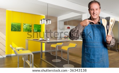 Man with an apron showing cooking tools in a design kitchen (pictures on the wall are mine so there are no copyright issues)