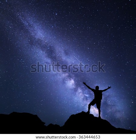 Milky Way. Night sky with stars and silhouette of a happy man with backpack and raised up arms. Space background