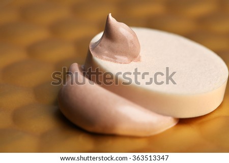 Makeup sponge with liquid foundation on abstract background