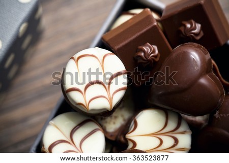 Assorted chocolate pralines on a wooden background. Romantic style