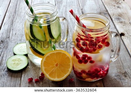 Detox water in mason jar glasses with lemon, cucumber and pomegranate against a rustic wood background