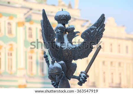 Close up details fence decorations with the Russian imperial double-headed eagle symbol covered with snow on Palace Square on the background of the Hermitage, St. Petersburg, Russia