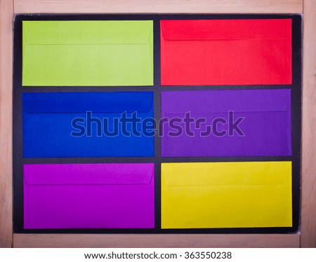 six colored envelopes on a black board