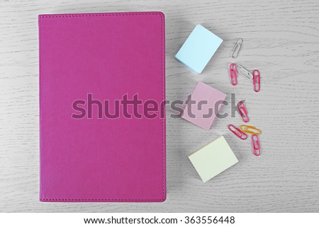 Coloured clips and stickers and notebook on white table