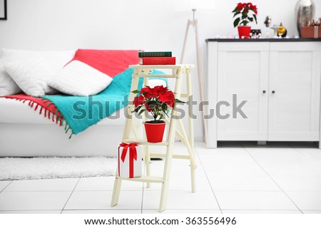 Christmas flower poinsettia and decorations on decorative ladder with Christmas decorations, on light background