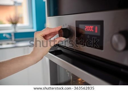 Woman regulates the temperature of the oven - 200C
