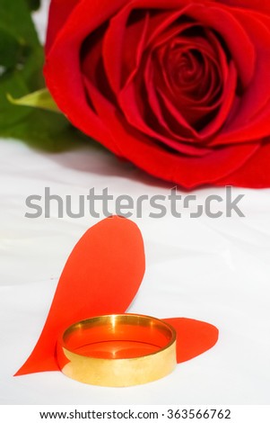 red rose and red paper heart cut out of paper, a ring of gold lying on a bright white background. Photos for Valentine's Day.