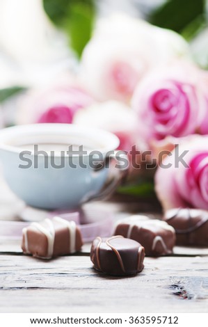 Pink roses, coffe and chocolate on the wooden table, selective focus