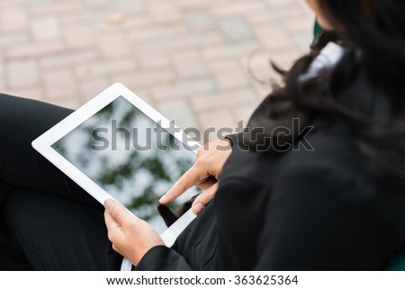 Over shoulder view of businesswoman using digital tablet computer outside