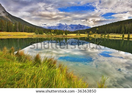 Lake in mountains surrounded by a wood and the cloudy sky above it. More magnificent pictures from the American and Canadian National parks you can look hundreds in my portfolio. Welcome!