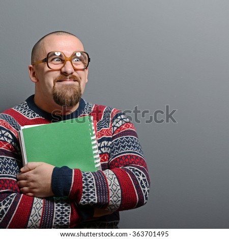 Portrait of a nerd holding book with retro glasses against gray background