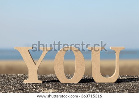 block wooden letters against blue sky, Word "you" 