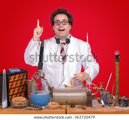 successful inventor at his desk with equipment on red background. Genius professor shows triumph for invention. Successful scientific research. The inventor of celebrating success in the lab. Royalty-Free Stock Photo #363720479