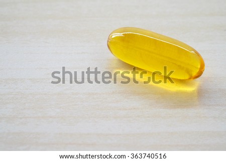 Oil pill, medicine, vitamin, closeup on wood background, oral medication