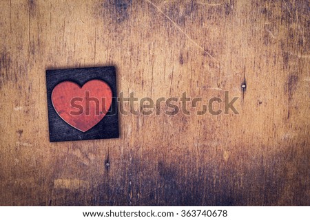 A single wooden heart in dirty vintage letterpress typescript on a aged wooden background.