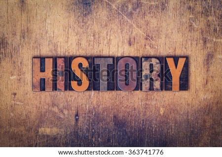The word "History" written in dirty vintage letterpress type on a aged wooden background.