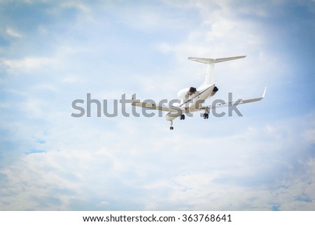 Small Passenger Jet Flying Against Vignette Sky Background With Landing Gear Down