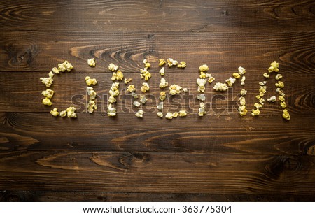 Conceptual shot of word Cinema written by popcorn and kernels on wooden background