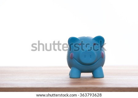 Smiling blue piggy bank on wooden table with isolated white background, concept for saving