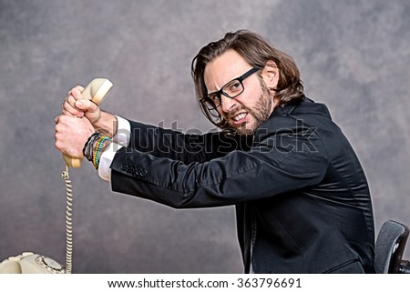 young angry businessman is choking his phone