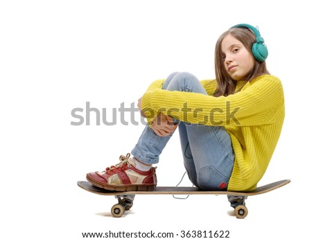 a pretty young girl posing with a skateboard, sitting on skate, listen a music