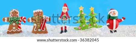 christmas characters like a snowman, gingerbread man and woman , with a skinny Santa standing in fake snow with xmas trees in the background