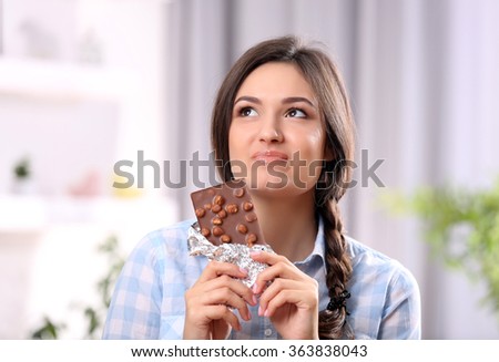 Portrait of beautiful young brunette with chocolate in the room , close up