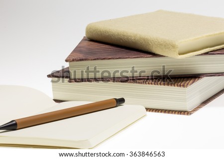 Stack of books and Pen on a Notebook