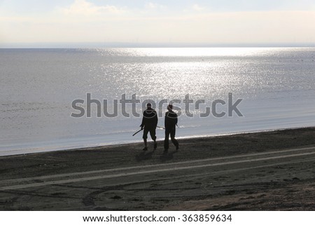 seascape silhouettes of travelers are on the seashore at sunset