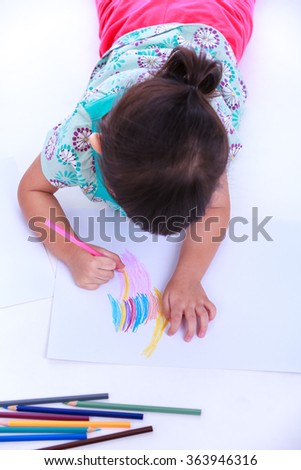Top view. Girl lie on the floor and drawing on paper. Concepts of creativity and education, strengthen the imagination of child. Studio shot. On white background.